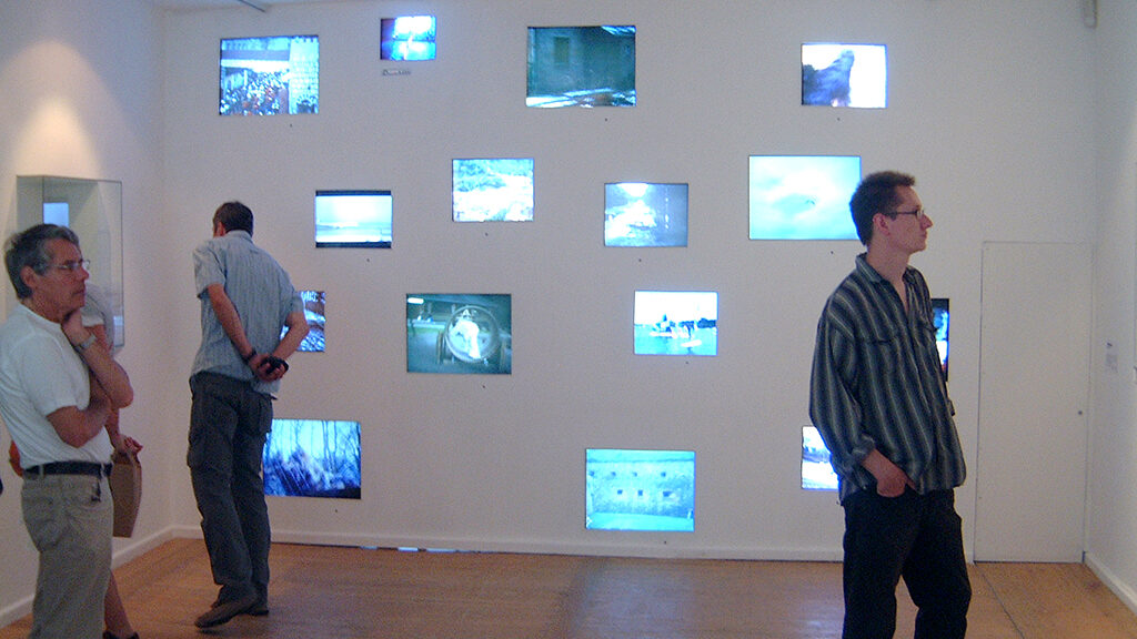 three men looking at the displayed televisions in the walls